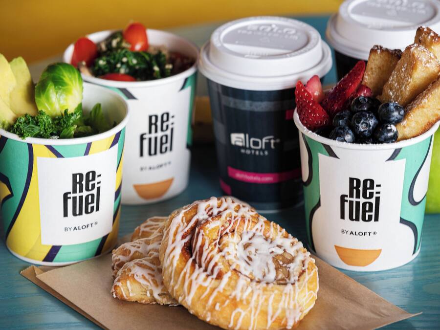 A table with food items and coffee cups labeled 'Re:Fuel' by Aloft Hotels.