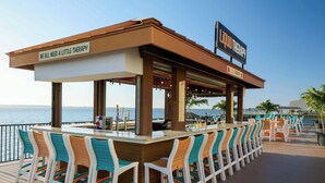 Eine Bar mit einem Schild, das 'LIQUID THERAPY' zeigt, und Blick aufs Meer.