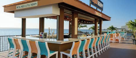 A bar area with a sign reading 'LIQUID THERAPY' and a view of the sea.