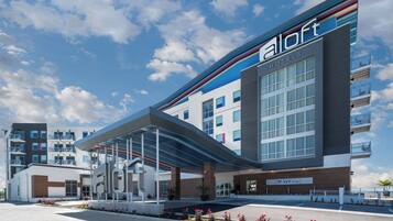A modern hotel with a covered entrance, a lounge area, and a parking lot.
