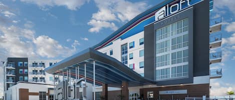 A modern hotel with a covered entrance, a lounge area, and a parking lot.