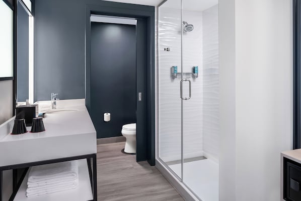 A modern bathroom with a glass shower enclosure, a white sink, and a dark wall. - Aloft by Marriott Ocean City (Ocean City)