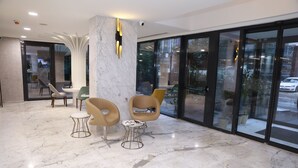 A modern lobby with marble flooring, contemporary chairs, and large glass doors leading outside. - Milord Hotel (Istanbul)