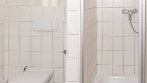 A bathroom with a toilet, a towel rack, and a shower area. - Mühlen Hotel Konschake (Burgen)