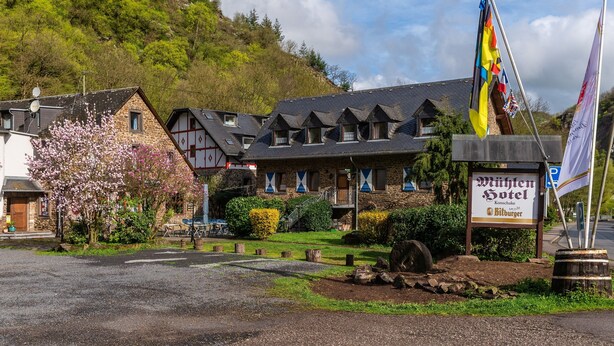 A traditional European hotel with stone walls and a signboard. - Mühlen Hotel Konschake (Burgen)