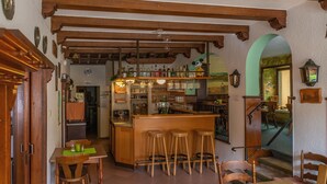 A bar area with wooden beams, stools, and a variety of bottles and glasses. - Mühlen Hotel Konschake (Burgen)