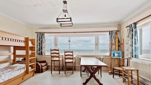 Ett rum med våningssängar, ett matbord, stolar och utsikt över havet.