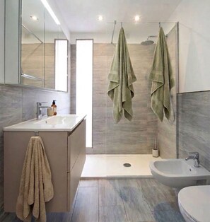 A modern bathroom with a bathtub, a sink, and a shower area. - Apartment LUISA in the Casa Corte in the heart of Malcesine (Malcesine)