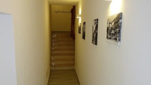 Un pasillo estrecho con suelo de madera y una escalera al final.