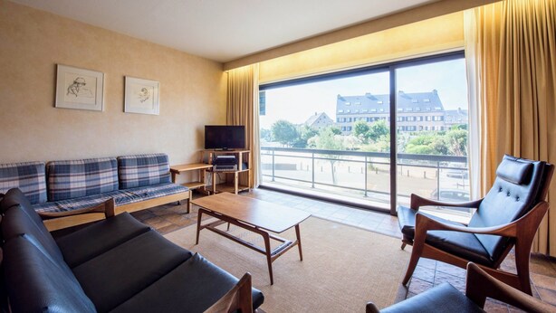 A modern hotel room with a sofa, armchairs, a coffee table, and a TV. - Zandstuyver 102 (Koksijde)