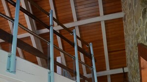 Un interior amb diversos nivells, una escala de fusta, un sofà i una làmpada penjada a la paret.
