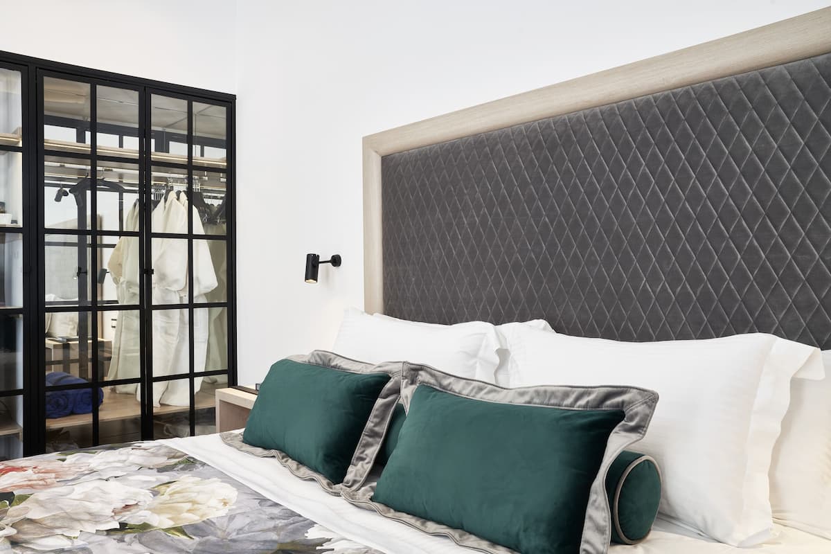 Une chambre à coucher comprenant un lit, une tête de lit, une table de chevet et une armoire contenant des vêtements.