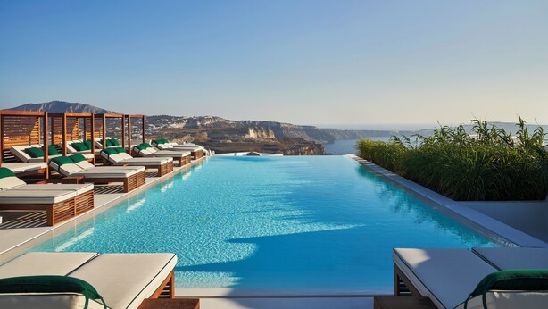 A pool with lounge chairs and a view of a mountainous landscape.