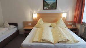 Ein Hotelzimmer mit einem Einzelbett, zwei Nachttischen und einem Beistelltisch mit einer Lampe.