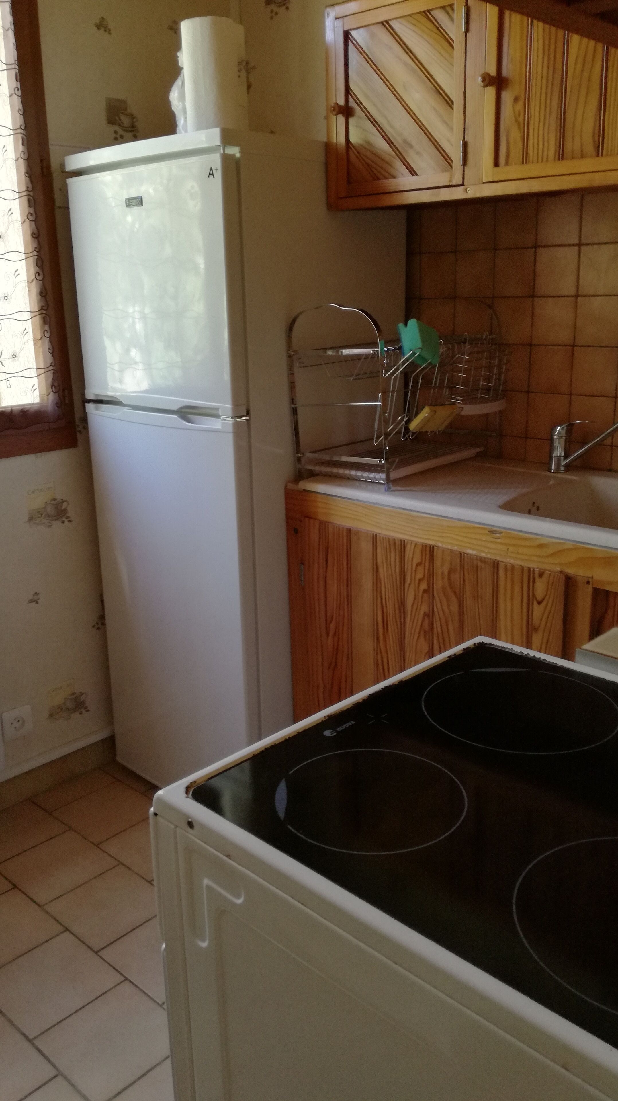 Une cuisine avec un réfrigérateur blanc, des placards en bois, un évier et une cuisinière.