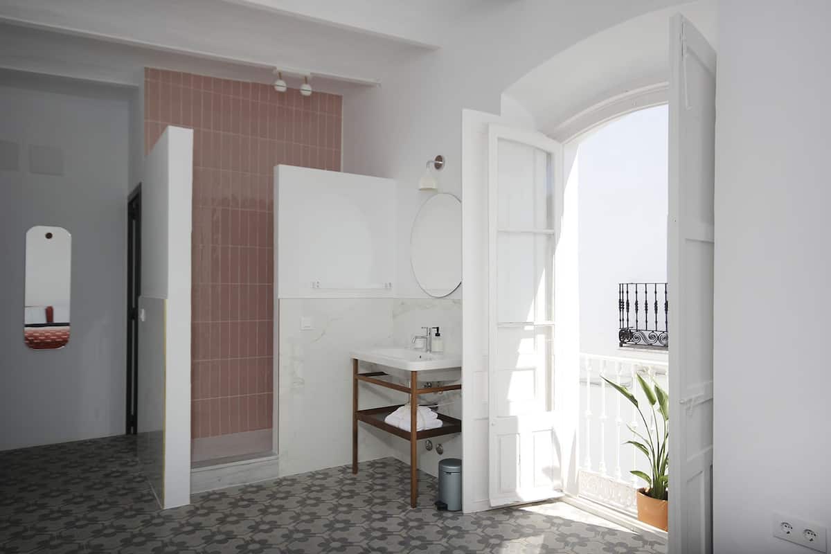 A modern bathroom with a white sink, a mirror, and a shower area.