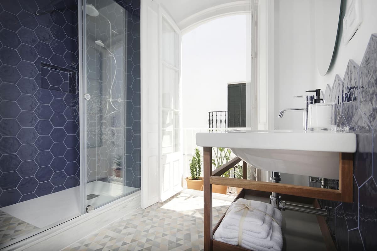 A modern bathroom with a glass shower, a white sink, and a view of the outdoors.