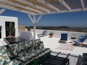 Una terraza en la azotea con un sofá, sillas y una mesa.