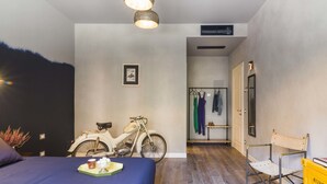 Une chambre à coucher avec un lit, un vélo, une chaise et un porte-manteau.