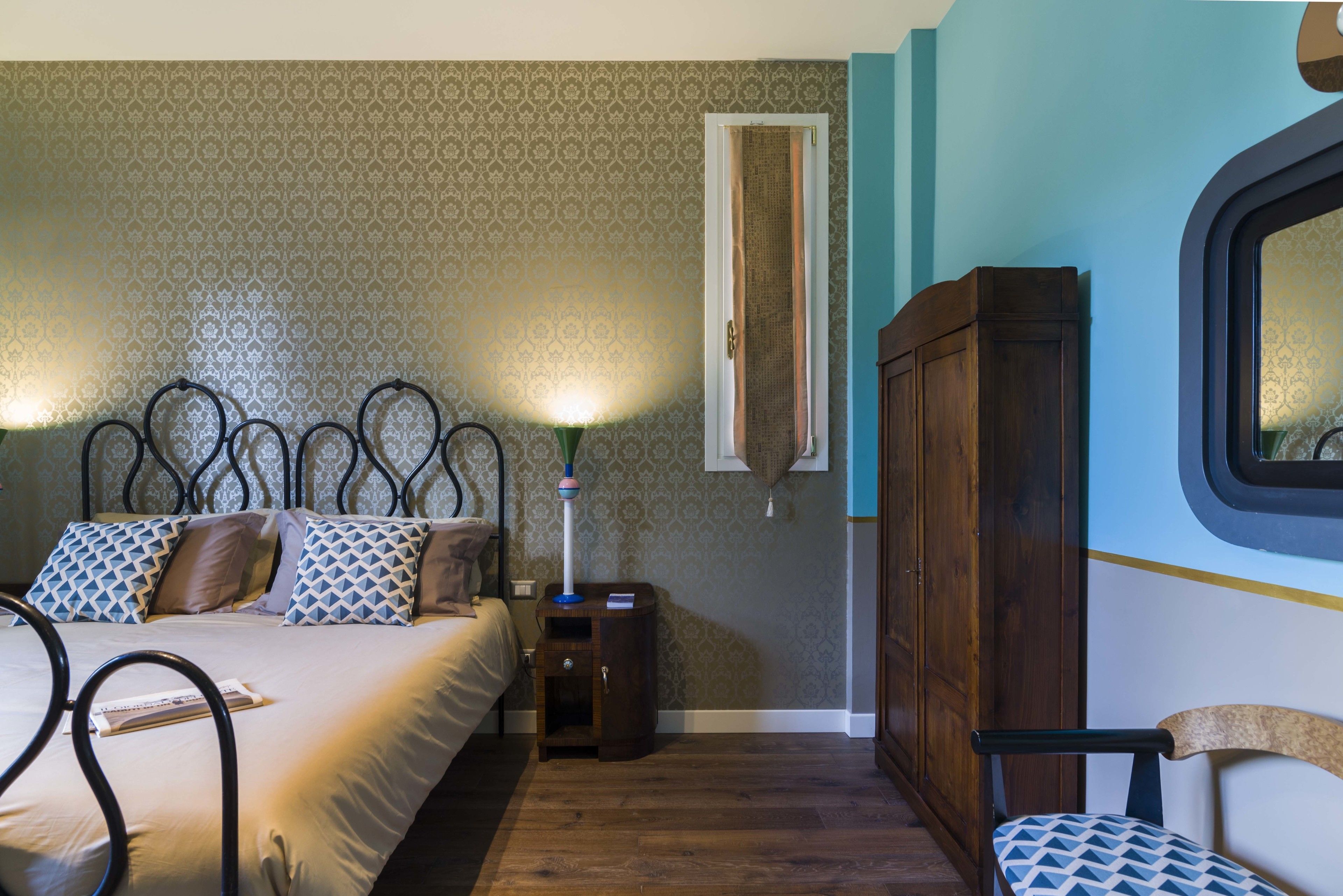 A bedroom with a bed, bedside table, lamp, wardrobe, and a chair.