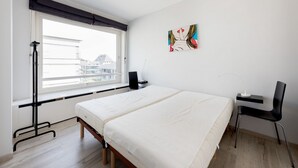Ett modernt sovrum med två sängar, ett skrivbord och en stol.