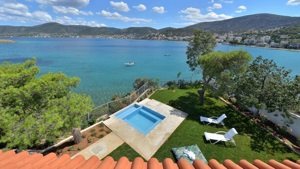 A pool with two lounge chairs, a clear view of the sea, and a mountainous backdrop. - Villa Portomare (Markopoulo Mesogaias)
