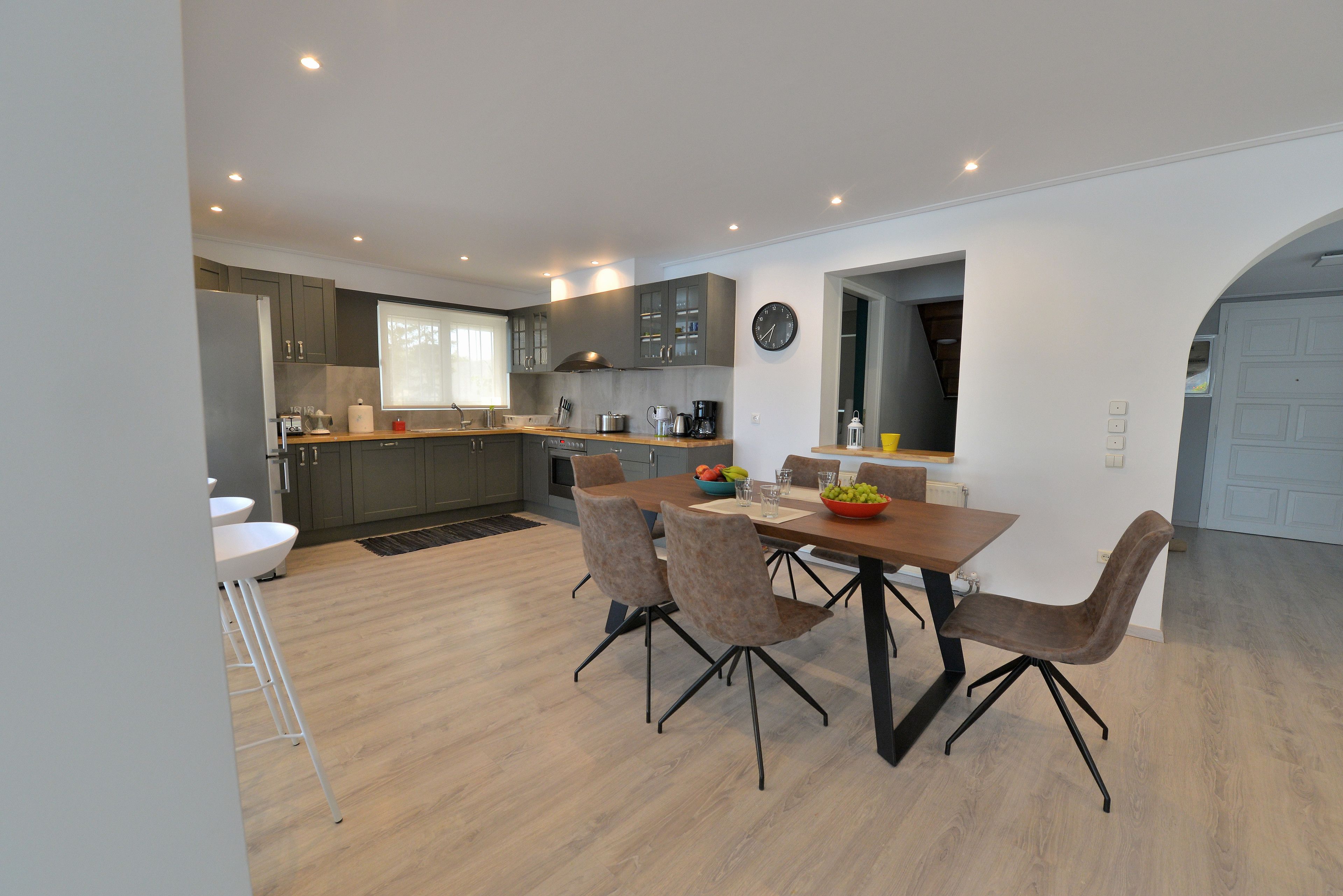 Una cocina moderna con gabinetes grises, una mesa de comedor de madera y un ventanal.