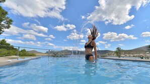 A swimming pool with clear blue water, surrounded by a fence and greenery. - Villa Portomare (Markopoulo Mesogaias)