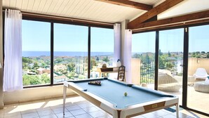 Ein Billardtisch in einem Raum mit großen Fenstern, die einen schönen Ausblick bieten.