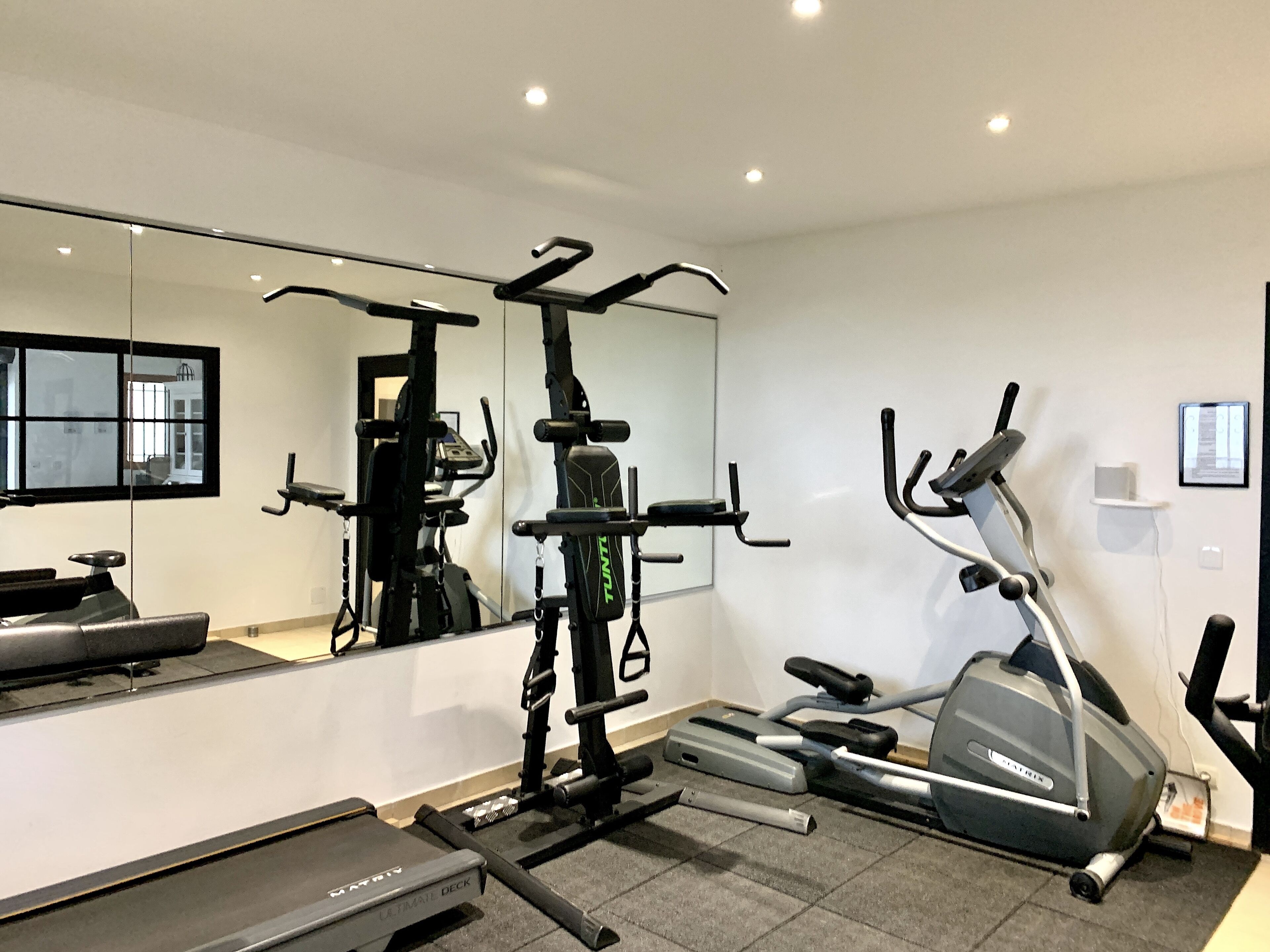 A home gym with a treadmill, weight bench, and various exercise machines.