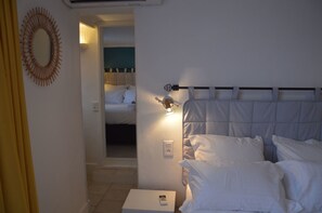 A hotel room with a bed, a bedside table with a remote control, a wall-mounted light, and a mirror. - Hotel Castellamar (Sainte-Maxime)