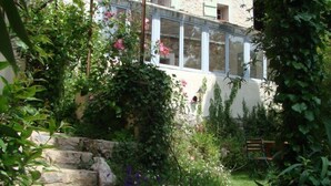 Un bâtiment en pierre doté d’un jardin, d’un banc en bois et d’un escalier menant à l’entrée.