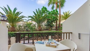 A balcony with a table set for two, surrounded by palm trees and a view of a cityscape. - Klayman Olivina Aparthotel (Arona)