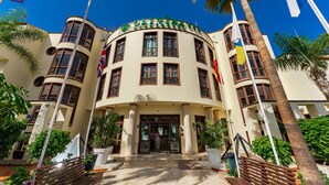 A hotel with a curved facade, multiple windows, and flags. - Klayman Olivina Aparthotel (Arona)