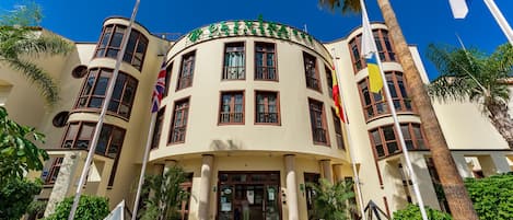 A hotel with a curved facade, multiple windows, and flags.