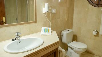 A bathroom with a sink, mirror, toilet, and hairdryer.