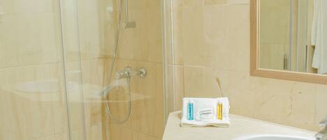 A bathroom with a glass-enclosed shower, a sink, and wooden cabinets.