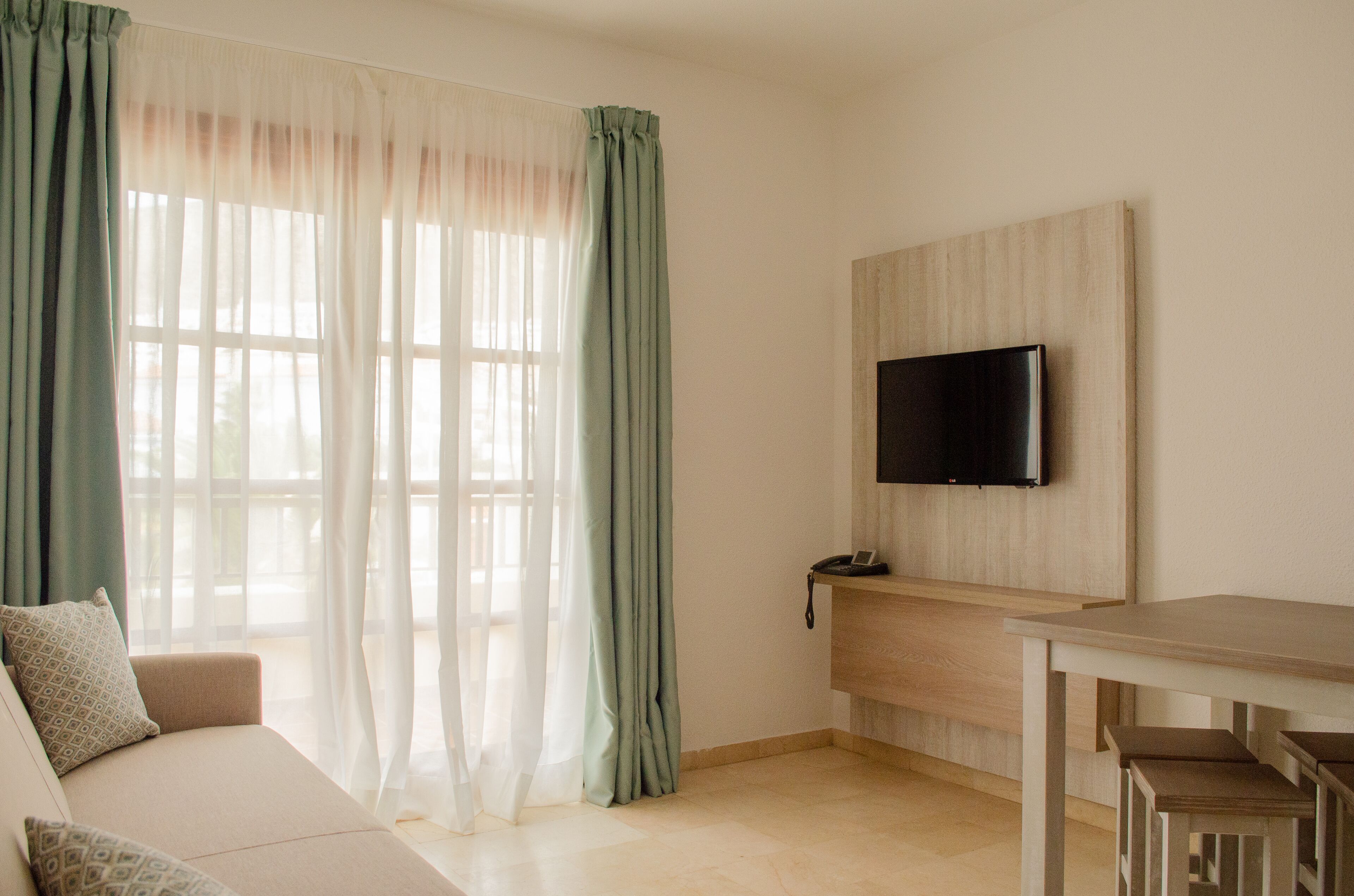 Una sala de estar moderna con un sofá, una mesa de comedor y un televisor montado en la pared.