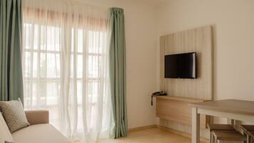 Una sala de estar moderna con un sofá, una mesa de comedor y un televisor montado en la pared.