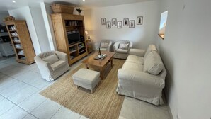 A modern living room with a sofa set, a wooden entertainment unit, and a television.