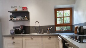 A modern kitchen with a built-in oven, a stainless steel sink, and a window with a view of greenery.