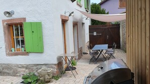 A patio area with a barbecue grill, outdoor seating, and a stone wall.