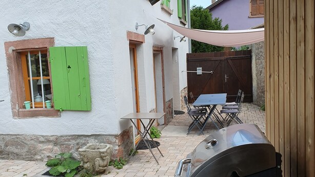 A patio area with a barbecue grill, outdoor seating, and a stone wall.
