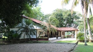 A house with a gravel driveway, a covered patio, and a lawn.
