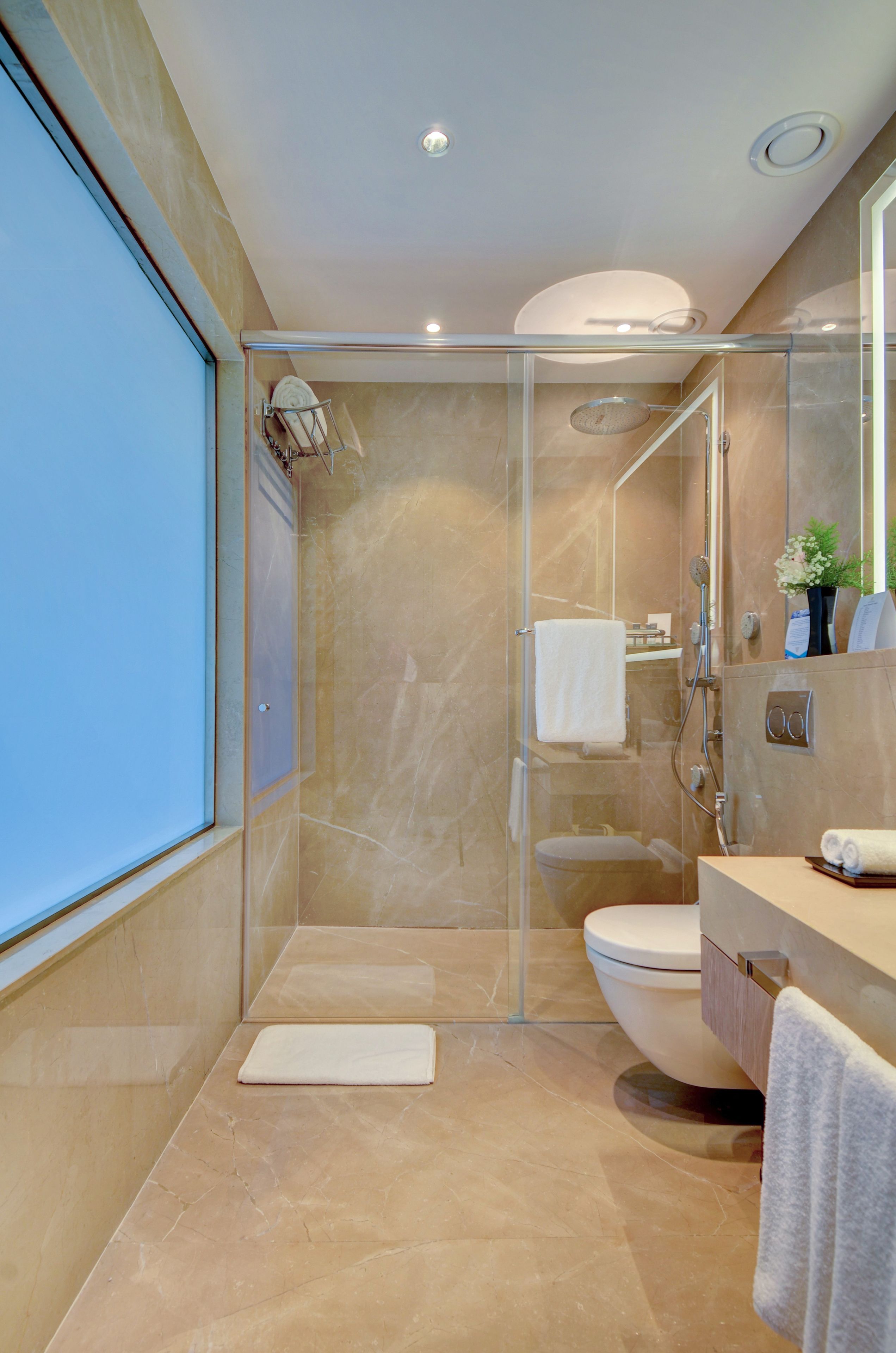 Un baño moderno con ducha envuelta en vidrio, inodoro y tocador con espejo.