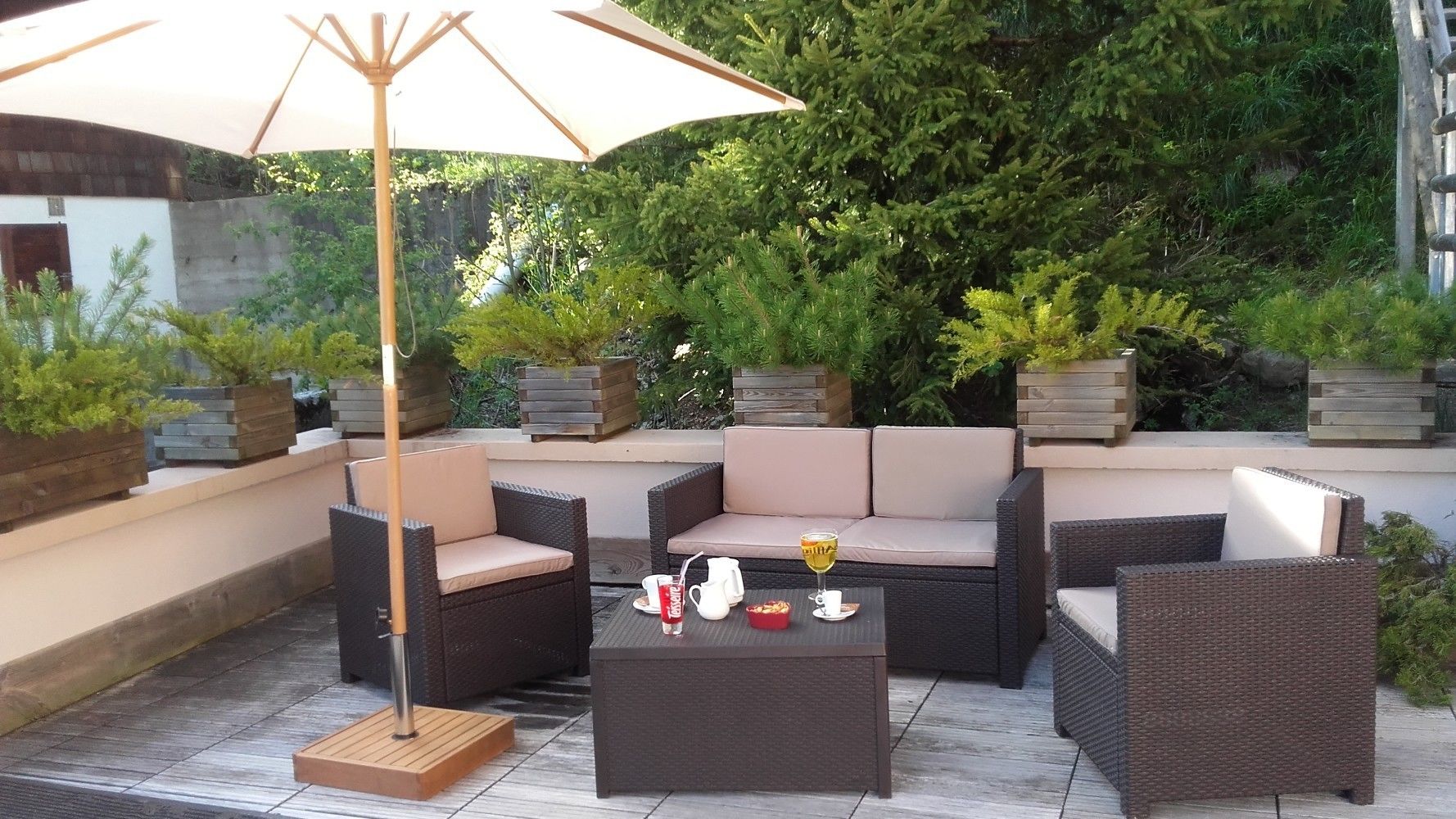 An outdoor patio area with wicker furniture, a coffee table, and an umbrella.