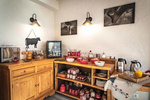 A kitchen with wooden cabinets, a refrigerator, and various kitchen items on the counter. - Hôtel L'Alpage (Le Grand-Bornand)