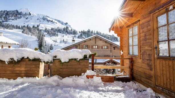 Une cabane en bois avec un toit enneigé et une clôture en bois.