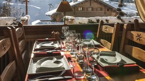 Une table de salle à manger en bois, pour quatre personnes, avec vue sur un paysage montagneux enneigé.