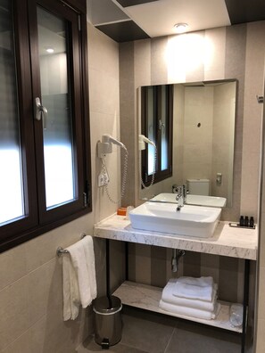 A modern bathroom with a large mirror, a white sink, and a towel rack. - Grecorooms (Toledo)